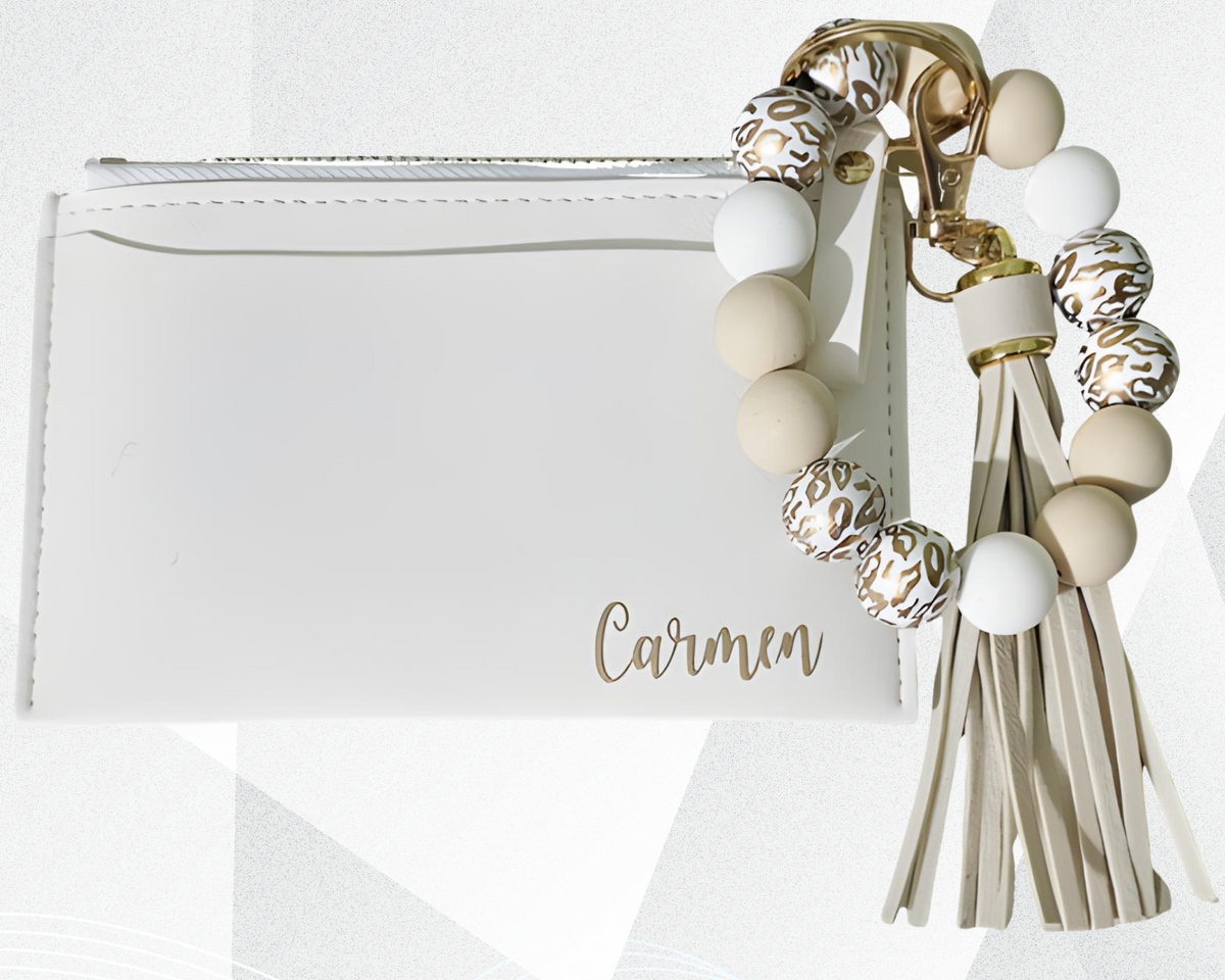 Bolso de mano blanco con un llavero decorativo con cuentas y borlas sobre fondo blanco.